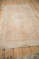 Vintage distressed Oushak rug seen from an angle, showing its soft texture and time-softened pattern.