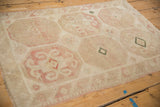 A close, angled view of the distressed pile and blush octagonal patterns on a vintage Turkish rug.