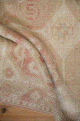 A soft fold reveals the textured, low pile and hand-knotted detail of a distressed vintage rug.