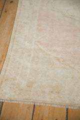 Side view of distressed Oushak rug showing low pile, intact selvage, and short end fringe.