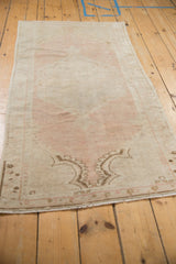 Angled lengthwise view of the vintage Oushak runner showing its distressed, faded pink and ivory palette.