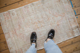 A small distressed Oushak rug with a soft, faded palette, viewed from above for scale.