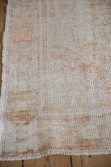 Close view of the worn pile showing the ivory and rust knot heads of a distressed rug.