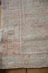 The worn, hand-knotted pile of a distressed Oushak rug showing ivory foundation and rust tones.