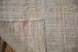 Corner of a distressed Oushak rug folded to show the hand-knotted foundation and secured side selvage.