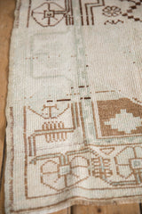 Distressed texture of hand-knotted Oushak rug with geometric brown and ivory motifs.