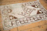Distressed Oushak rug corner with geometric border, minor medallion, and softened pile.