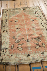 Decorative distressed Anatolian rug, angled to show the pale ruby tree of life motif.