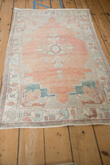 Full length view of a distressed vintage Oushak rug with a faded cantaloupe melon field and geometric motifs.