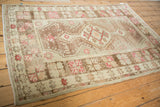 Distressed vintage Oushak rug with faded starburst border and abrashed ground.