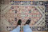Detail of the distressed vintage Anatolian rug's quatrefoil medallion, finned buds, dusty blush.