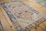 Distressed Anatolian rug corner showing blush field, cobalt blue borders, and varied floral patterns.