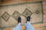 Distressed Anatolian rug, ivory field with bronze and green medallions, prominent knot head wear.