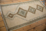 Distressed vintage Anatolian rug detail: ivory pile wear, bronze medallion, and zig-zag border.