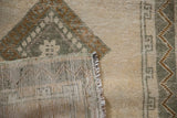Distressed vintage Anatolian rug corner showing geometric ivory pile and woven back.