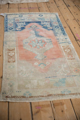 Distressed Oushak rug corner with heavy cantaloupe abrashes, beige spandrel, and faded blue details.