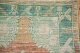Worn knot heads on the geometric border of a vintage Oushak in mint and terracotta.