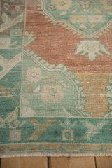 Close-up showing the floral arabesque design and low-pile texture of a distressed Oushak rug.