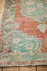 Low-pile texture and geometric border detail on a vintage distressed Oushak rug.