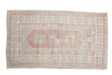 Vintage distressed Oushak rug with a central floral medallion in time-softened aubergine, ivory, and silver.