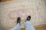 Low-pile texture of a distressed Oushak rug with dusty aubergine and ivory colors.