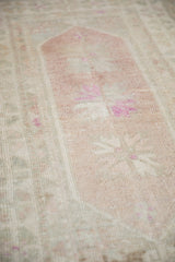 Angled close-up showing the distressed texture and mostly even wear on a vintage Oushak rug.