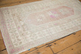 Low angle view of a distressed Oushak rug showing its time-softened magenta and ivory colors.