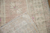 A folded corner of a distressed Oushak rug showing the hand-knotted back and low wool pile.