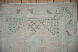 Distressed vintage Oushak rug's worn pile showcasing pale mint, dusty blush, charcoal geometric motifs.