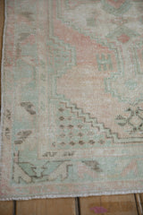 Distressed Oushak rug pile with mostly even wear, showing pale blush and mint green patterns.