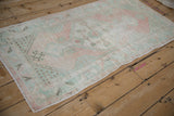 Distressed Oushak rug corner detail, soft blush, mint, ivory tones, showing low pile wear.