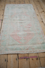 Vintage distressed Oushak rug with soft blush and mint hues and aged texture.