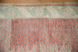 Worn hand-knotted pile showing a mint green serrated leaf border and raspberry field with abrashes.
