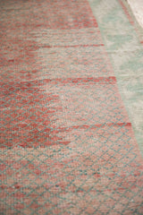 Close-up of the vintage Turkish rug's even wear, showing raspberry and mint green abrashes.