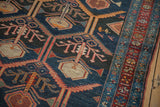 Antique Malayer rug close-up: germinating plant design, serrated leaves, navy and madder red.