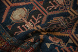 Folded antique Malayer rug showcasing serrated leaf patterns and a detailed multicolor border.