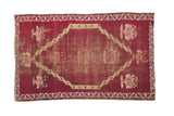Antique Anatolian rug with a large medallion and floral spandrels on a distressed raspberry red ground.