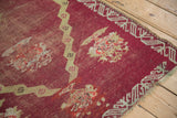 Worn raspberry red pile and meandering border on a hand-knotted antique Anatolian rug corner.