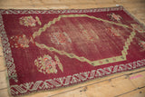 Worn texture of an antique Anatolian rug's raspberry red field surrounding a geometric sand colored medallion.