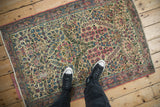 Vintage Kerman rug with intricate thousand flower motif on ivory field, soft reds, and blues.