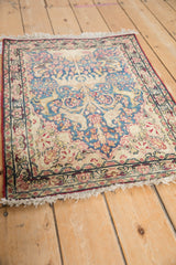 Antique Kerman rug corner, showcasing its detailed border in red, blue, and ivory with fringe.