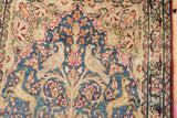 Denim blue field and detailed antique ivory bird with red blossoms on Kerman rug.