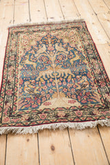 Antique Kerman pictorial rug's floral border, antique ivory, red tones, blue field, and white fringe.