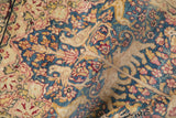 Antique Kerman pictorial rug detail: a deer amid blossoms, denim blue, dusty gold, and soft pile.