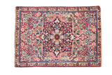 Antique Kerman rug mat: starburst medallion, floral vines, cochineal red, navy, and sand tones.