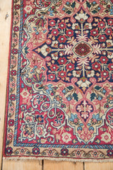 Antique Kerman rug corner: narrow floral border with sand ground, cochineal red field, minor end loss.