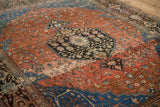 Angled detail of a vintage Sarouk rug's navy medallion, red field, and time-softened pile.