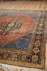 Corner detail of a vintage Sarouk rug featuring a blue arabesque spandrel and a dark floral main border.