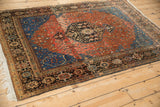 Full angled view of a vintage Persian Sarouk rug's red field and sapphire blue spandrels.