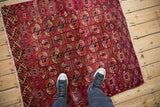 Antique Turkmen rug with a field of red and navy geometric guls shown to scale.